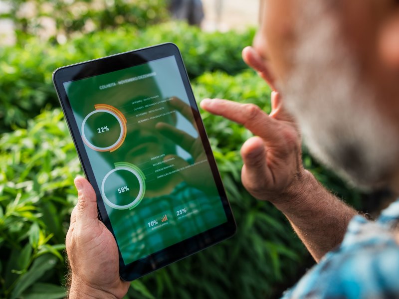 A farmer uses a tablet to analyze crop data outdoors