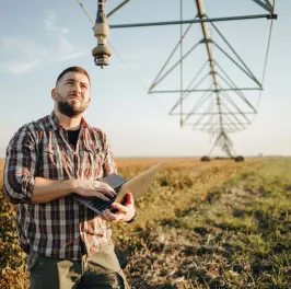 Young farmer standing in wheat field and setup irrigation system