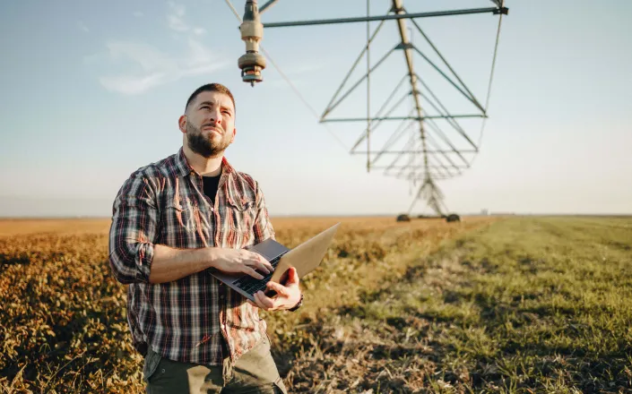 Young farmer standing in wheat field and setup irrigation system
