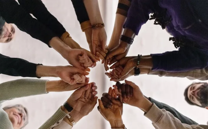 Low angle view of group of people in circle and holding their fists together