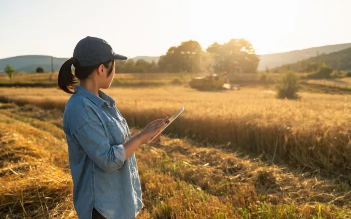 Female farmer using a tablet to control combine harvester