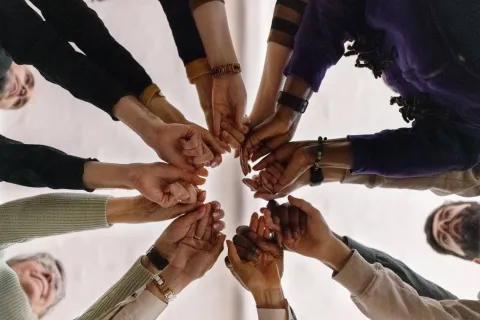 Low angle view of group of people in circle and holding their fists together